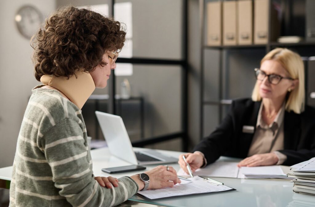 young-woman-with-neck-injury-filling-documents-2023-11-27-05-26-31-utc